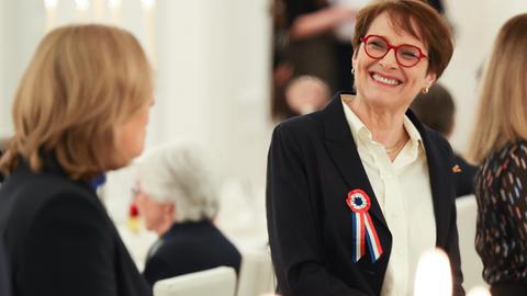 Hélène Miard-Delacroix trägt eine rote Brille und eine Brosche in den französischen Nationalfarben. Sie schaut zur Seite und lacht die Person links im Bild (Bundestagspräsidentin Bärbel Bas, nur von hinten zu sehen) an. Hélène Miard-Delacroix trägt eine rote Brille und eine Brosche in den französischen Nationalfarben. Sie schaut zur Seite und lacht die Person links im Bild (Bundestagspräsidentin Bärbel Bas, nur von hinten zu sehen) an.