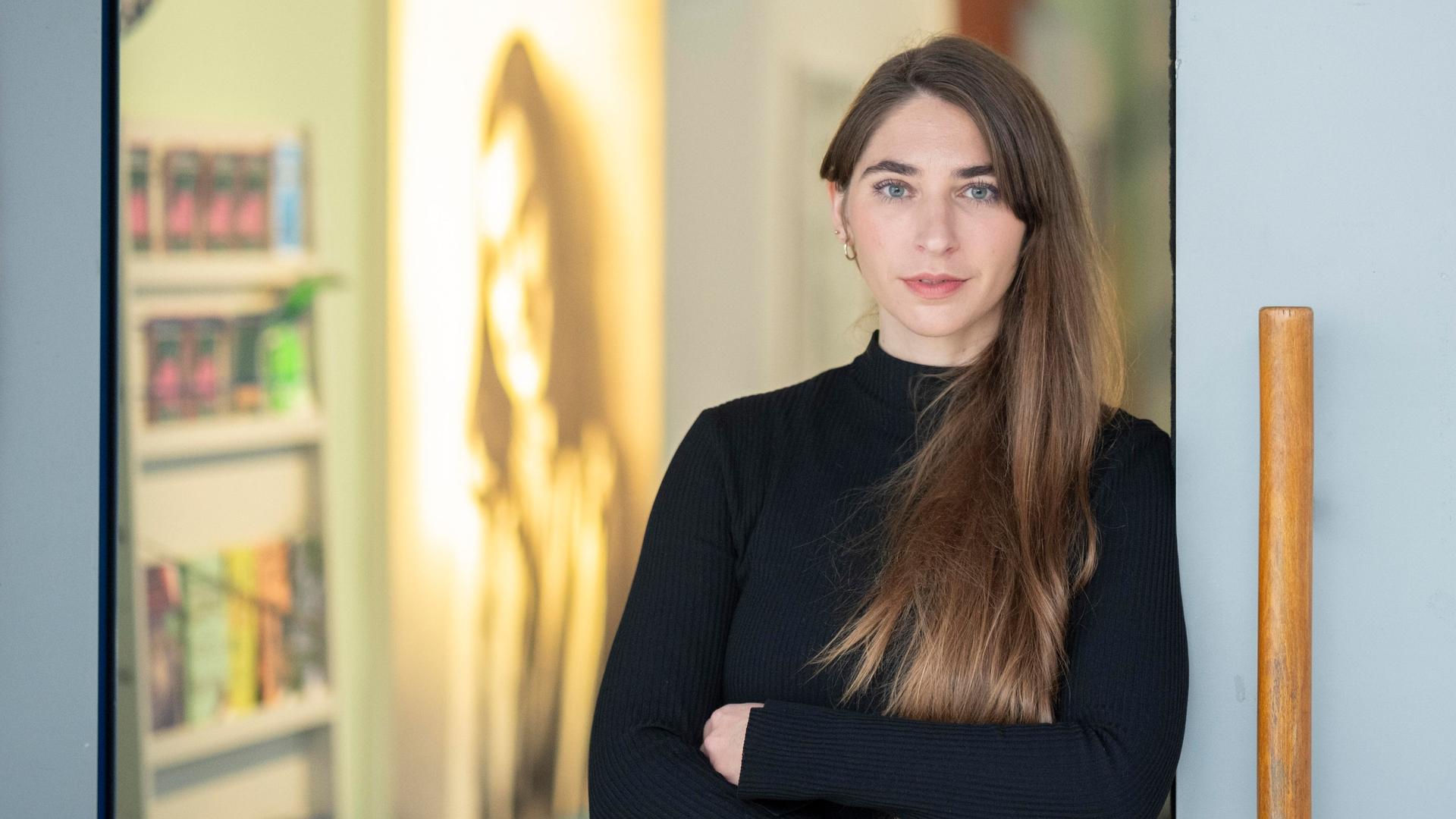 Deborah Schnabel steht am Eingang zu einem Ausstellungsraum, im Hintergrund ist ein Porträt von Anne Frank zu sehen.