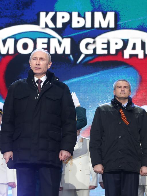 Russlands Präsident Wladimir Putin (vorn) mit Politikern und Soldaten von der annektierten Halbinsel Krim bei einer Feier auf dem Roten Platz in Moskau.
