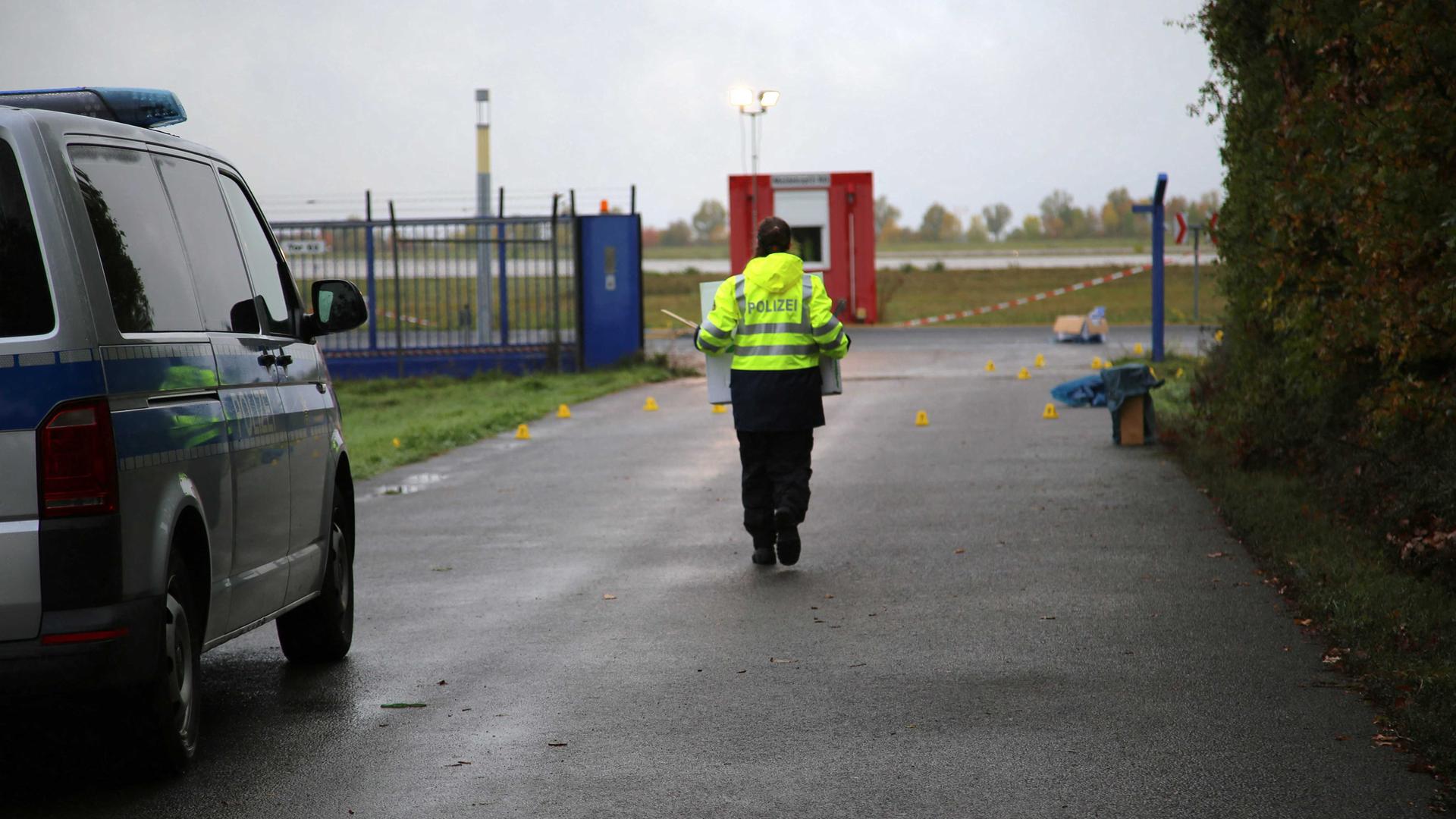 Ein beschädigter Zaun sorgt am Flughafen Leipzig/Halle für einen Polizeieinsatz. Ein Beamter läuft am Flughafengelände in der Nähe des abgesperrten Tatorts. 