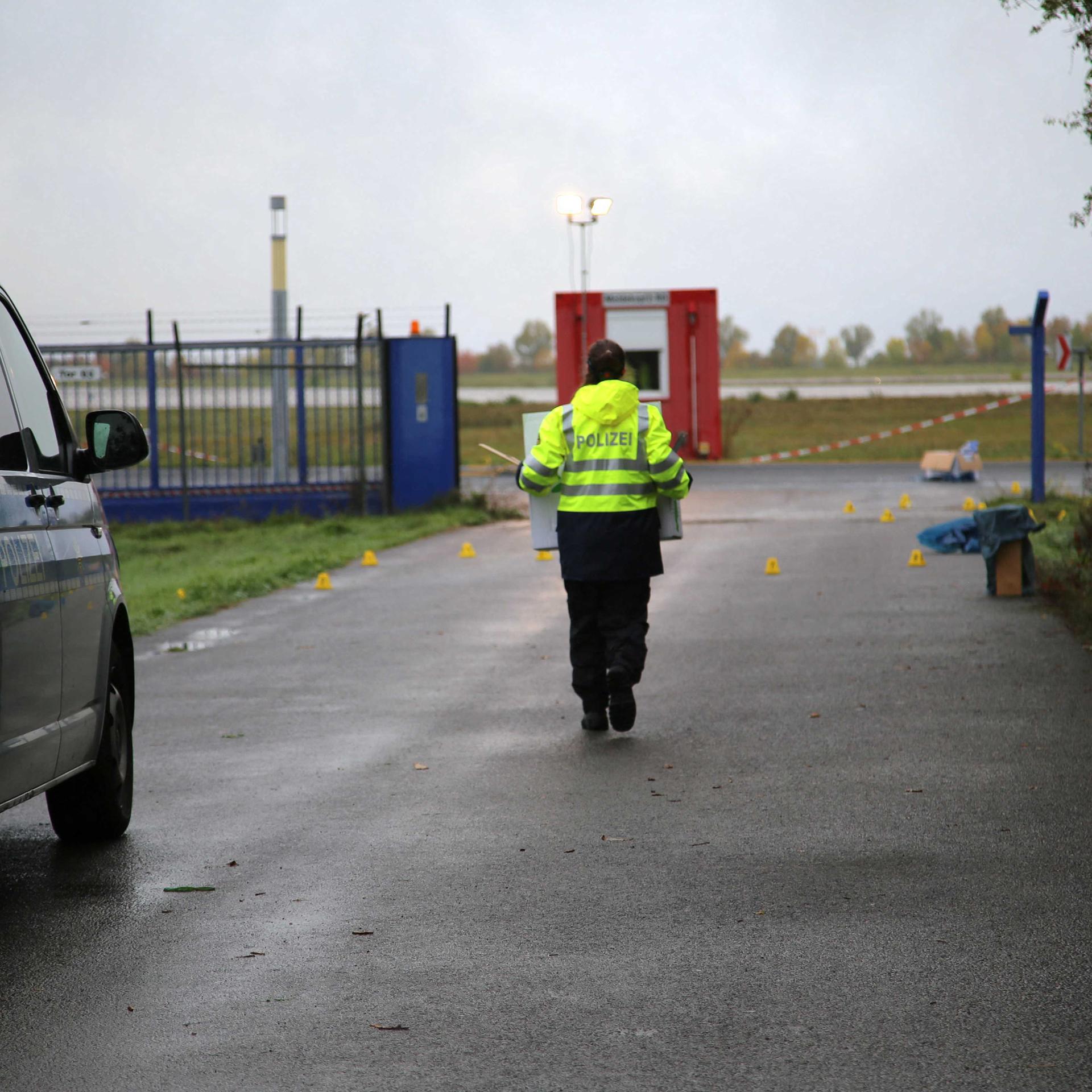 Ein beschädigter Zaun sorgt am Flughafen Leipzig/Halle für einen Polizeieinsatz. Ein Beamter läuft am Flughafengelände in der Nähe des abgesperrten Tatorts. 