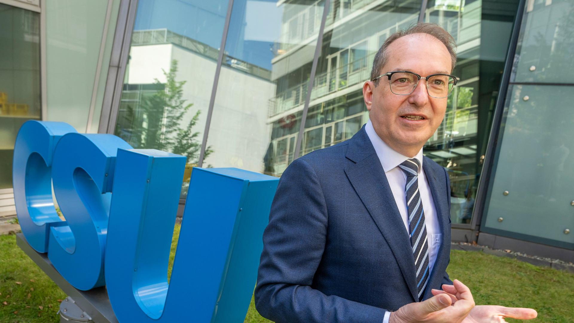 Der designierte Bundesinnenminister Alexander Dobrindt steht im Innenhof der CSU-Parteizentrale neben dem CSU-Logo.