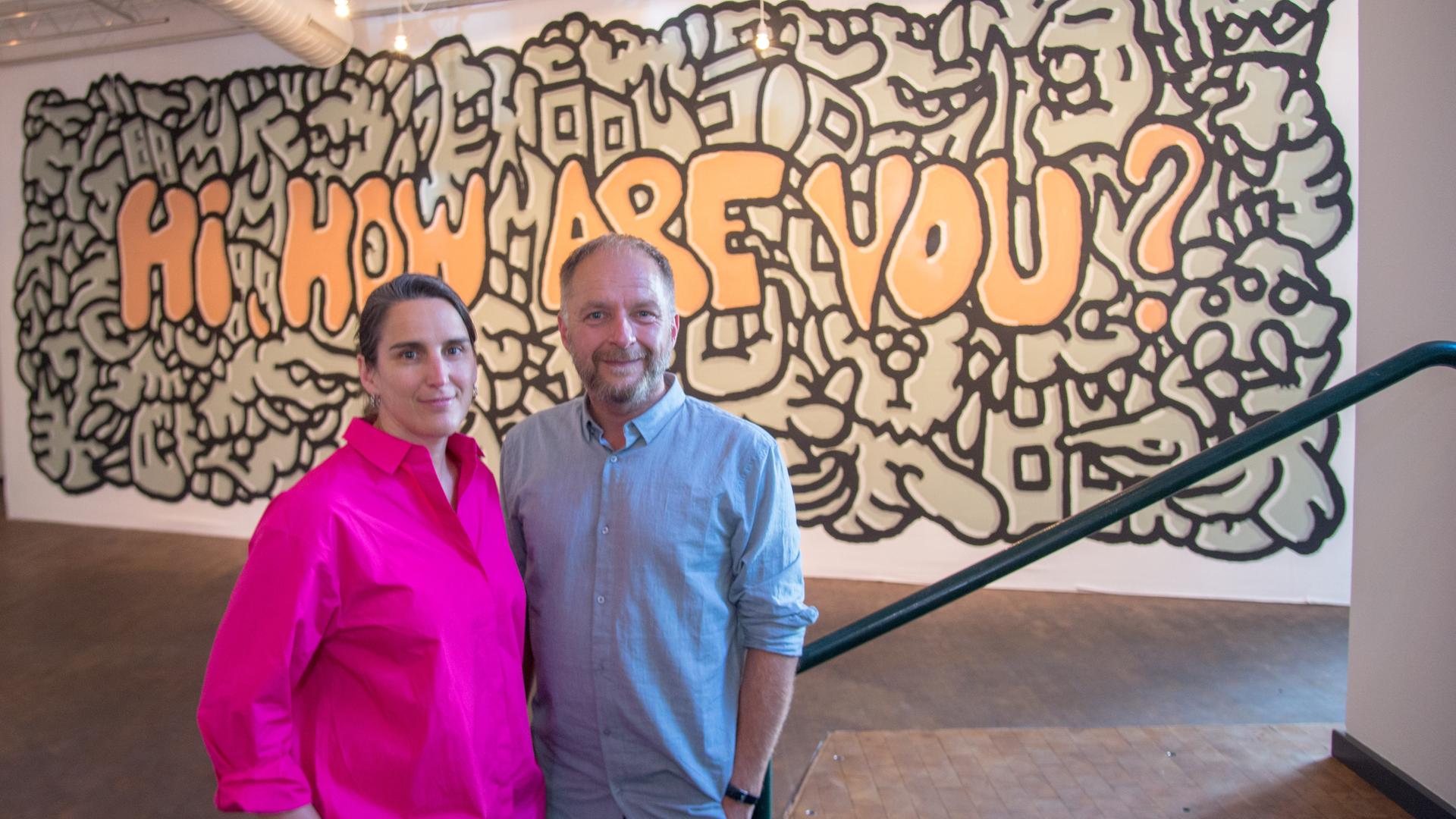 Anna Wagner und Marcus Droß, das neue Leitungsteam des Künstlerhauses Mousonturm, nach dem Pressegespräch zu ihrer neuen Aufgabe. Im Hintergrund ein Graffito mit dem Schriftzug "Hi, how are you". 