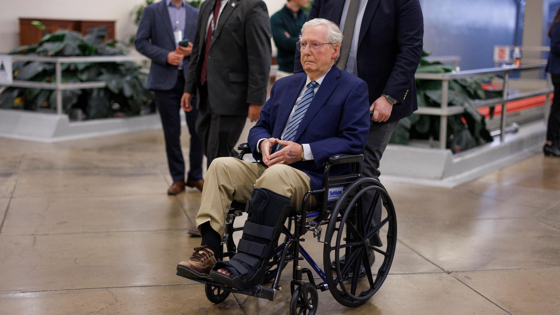 Senator Mitch McConnell wird im Rollstuhl geschoben