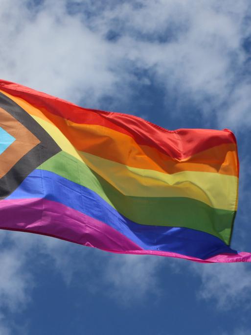 Regenbogenflagge vor bewölktem Himmel