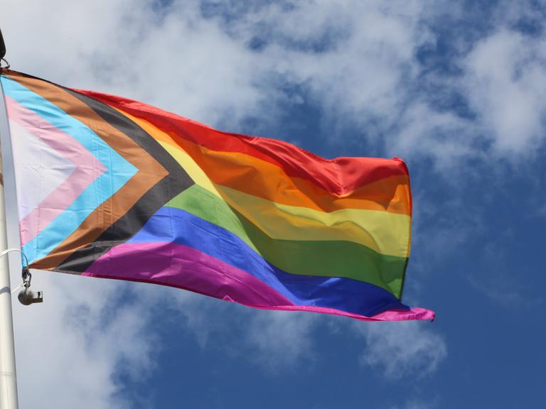 Regenbogenflagge vor bewölktem Himmel