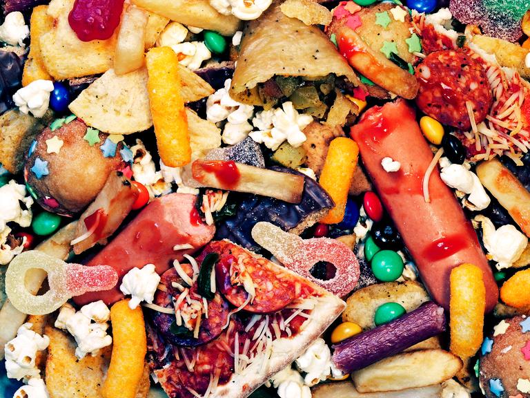 Bunte Lebensmittel im Müll: Pizza, Würstchen mit Ketchup, Muffins u.a.