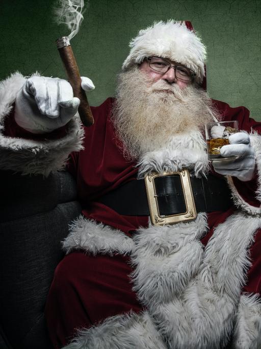 Ein dicker Weihnachtsmann sitzt mit Zigarre und Whiskey entspannt in einem breiten Sessel vor gründer Wand.