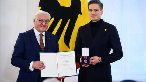 Theodor Rüber steht neben Bundespräsident Frank-Walter Steinmeier. Rüber hält die Bundesverdienstmedaille in den Händen, Steinmeier die dazugehörige Urkunde.