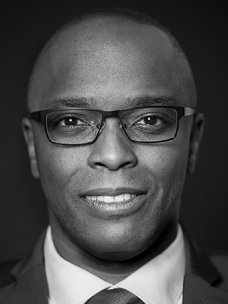 Frontales schwarz-weiß Porträt von Thomas Kapapa, der freundlich in die Kamera schaut.