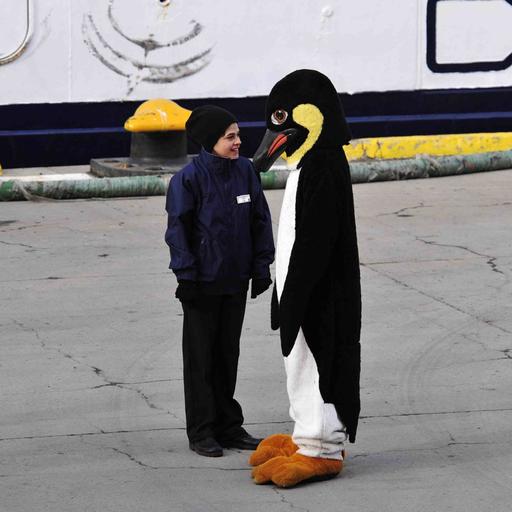 Ein älteres Kind steht einer Person in Pinguinkostüm gegenüber