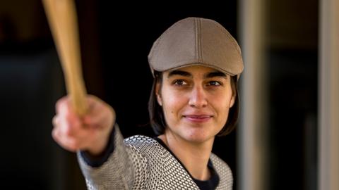 Leonie Klein mit Mütze lächelt in die Kamera, während sie zwei Schlegel mit ihrer rechten Hand nach vorn streckt.