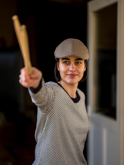 Leonie Klein mit Mütze lächelt in die Kamera, während sie zwei Schlegel mit ihrer rechten Hand nach vorn streckt.