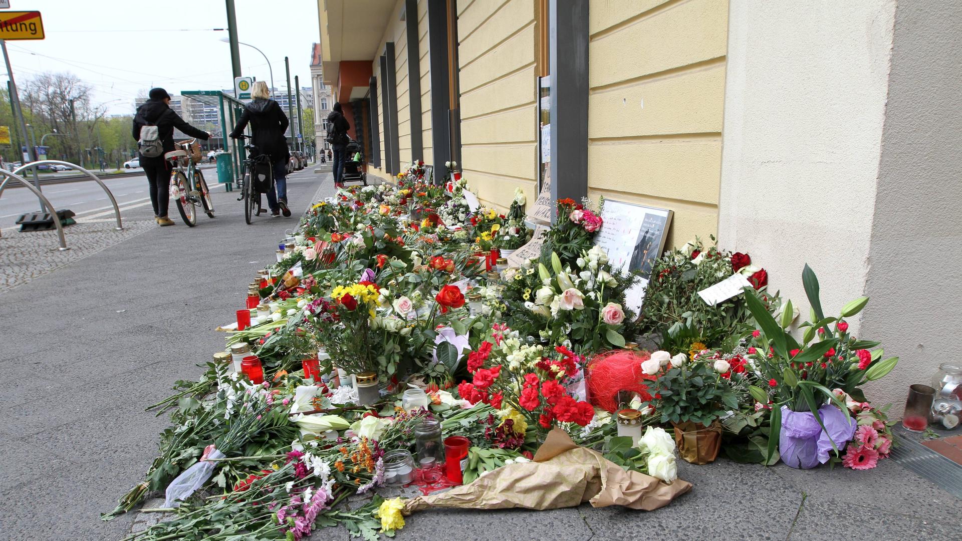 Viele Blumen liegen vor einem Haus zum Gedenken