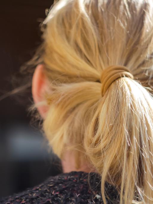 Nahaufnahme einer Frau mit blondem Pferdeschwanz von hinten.