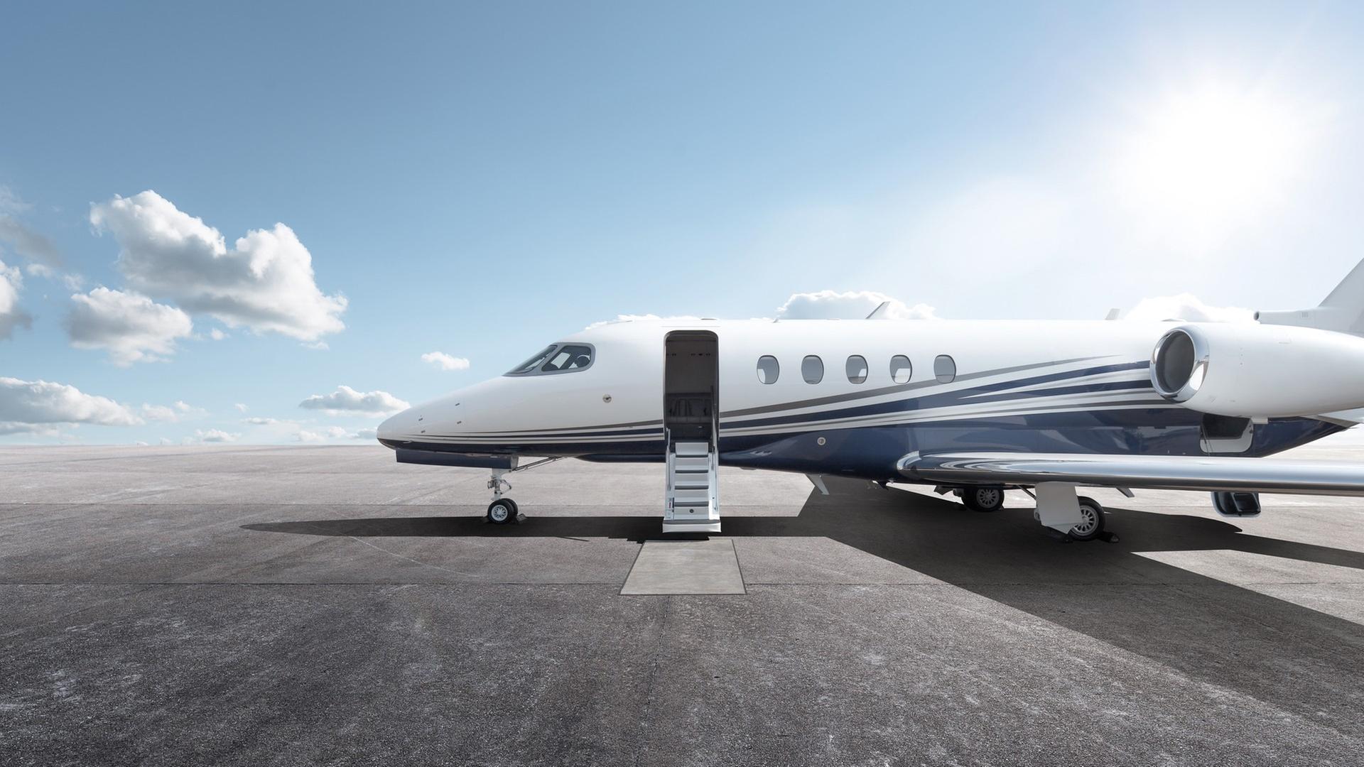 Ein Privatflugzeug mit geöffnetem Einstieg steht bei Sonnenschein auf einem Flugplatz.
