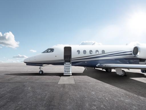 Ein Privatflugzeug mit geöffnetem Einstieg steht bei Sonnenschein auf einem Flugplatz.