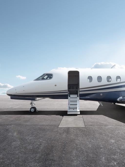 Ein Privatflugzeug mit geöffnetem Einstieg steht bei Sonnenschein auf einem Flugplatz.