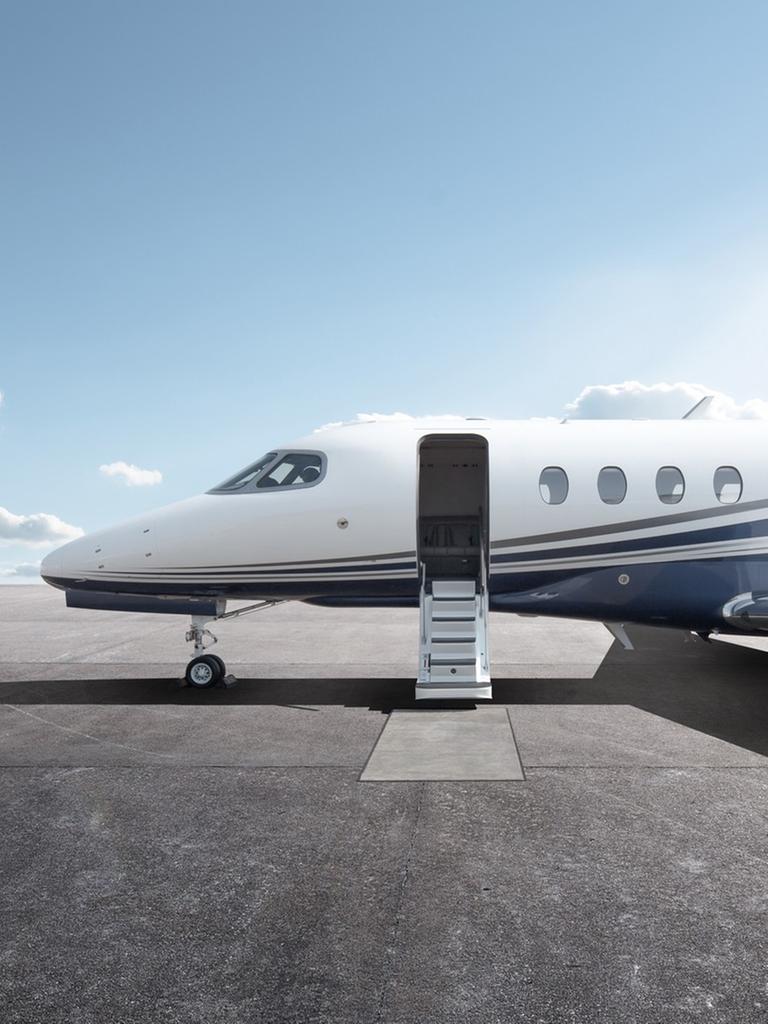 Ein Privatflugzeug mit geöffnetem Einstieg steht bei Sonnenschein auf einem Flugplatz.
