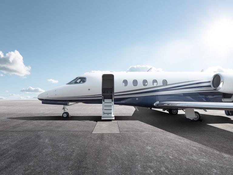 Ein Privatflugzeug mit geöffnetem Einstieg steht bei Sonnenschein auf einem Flugplatz.