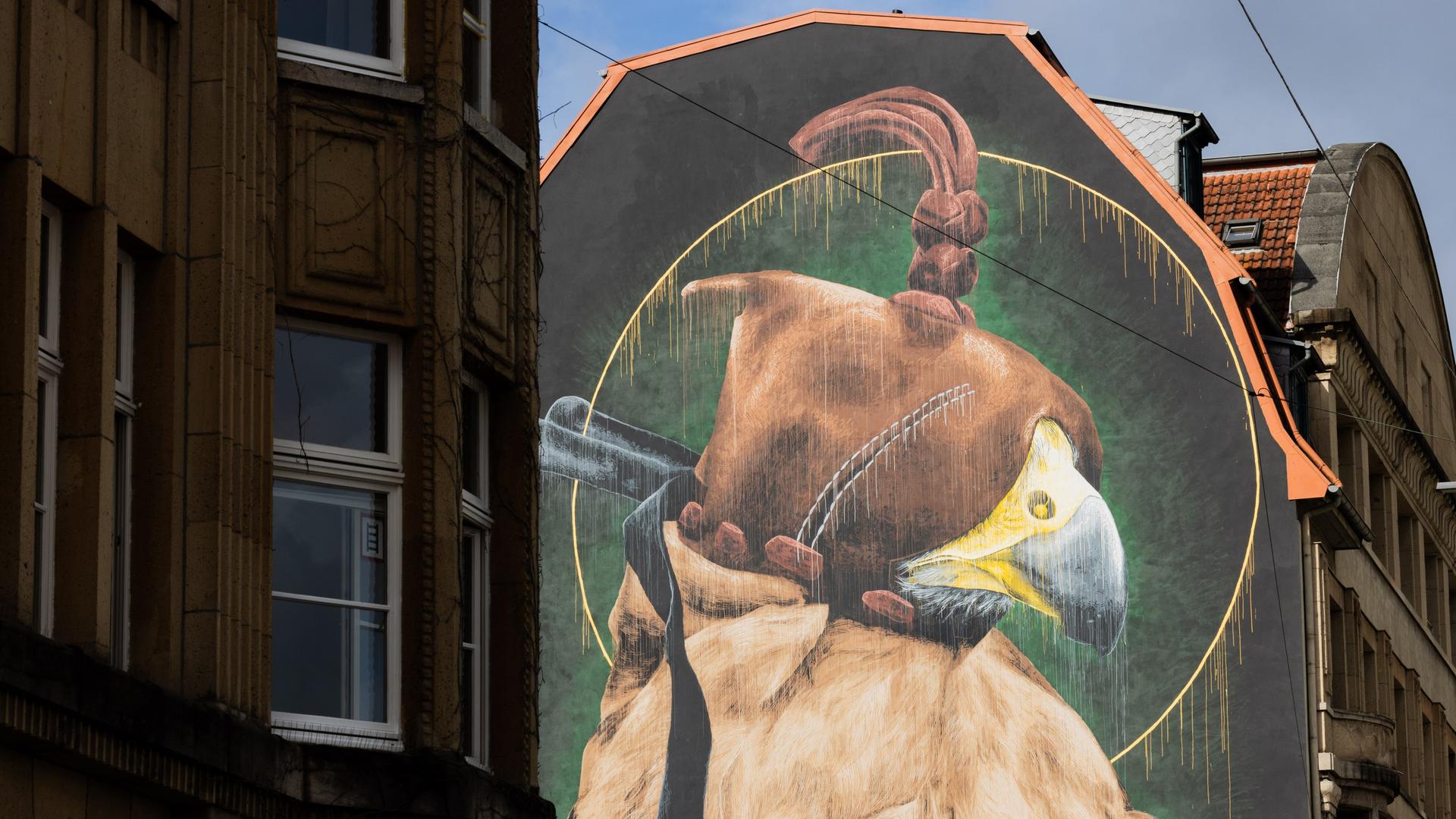 Auf einer Hauswand ist im Rahmen des Projekts "Urbaner Kunstraum Wuppertal" (UKW) ein Greifvogel zu sehen, dem eine Haube aufgesetzt ist. Auf einer Hauswand ist im Rahmen des Projekts "Urbaner Kunstraum Wuppertal" (UKW) ein Greifvogel zu sehen, dem eine Haube aufgesetzt ist.