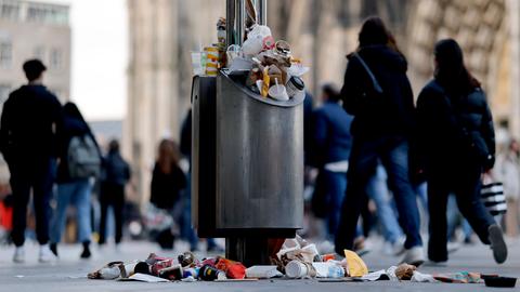 Ein Mülleimer in einer Fußgängerzone nahe des Kölner Dom quillt über.