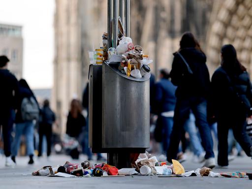 Ein Mülleimer in einer Fußgängerzone nahe des Kölner Dom quillt über.