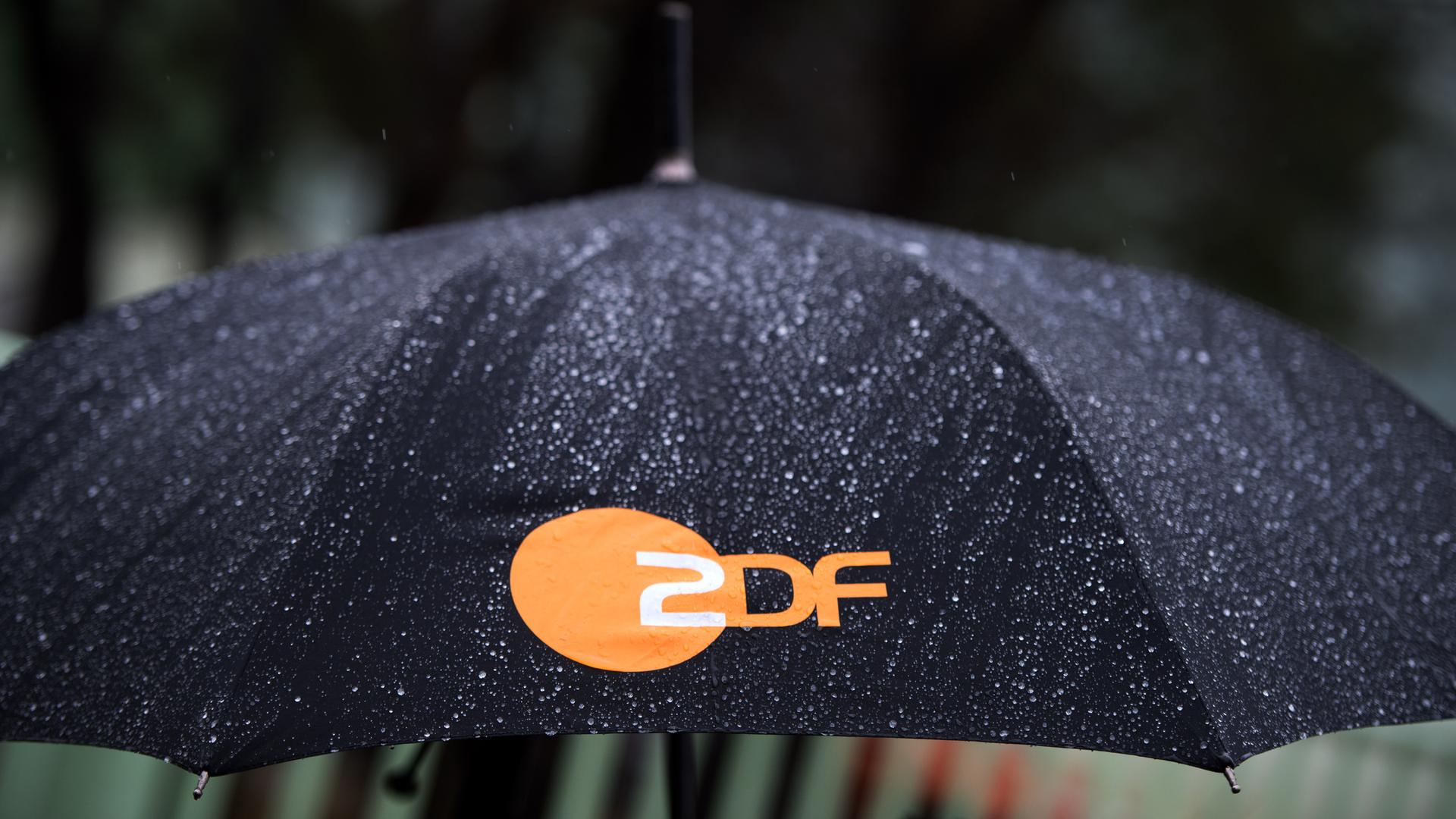Regen fällt auf einen Regenschirm mit dem Logo des ZDF