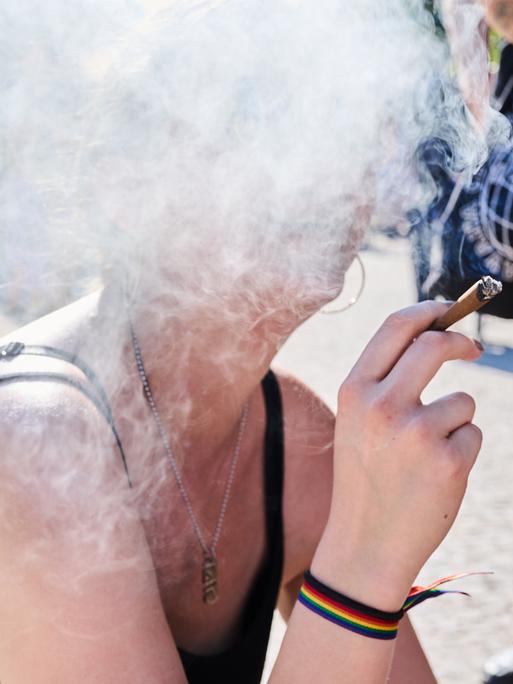 Eine Demonstrantin raucht einen Joint bei der Hanfparade. Ihr Gesicht ist hinter einer Rauchwolke verborgen. Die Hanfparade ist laut Angaben der Veranstalter die größte und traditionsreichste Demonstration für Cannabis in Deutschland.