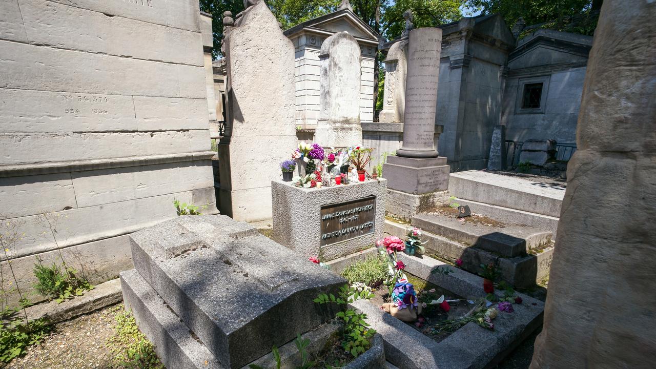Historische Grabstätten auf dem Friedhof Père Lachaise in Paris. Eine ist mit Blumen geschmückt.