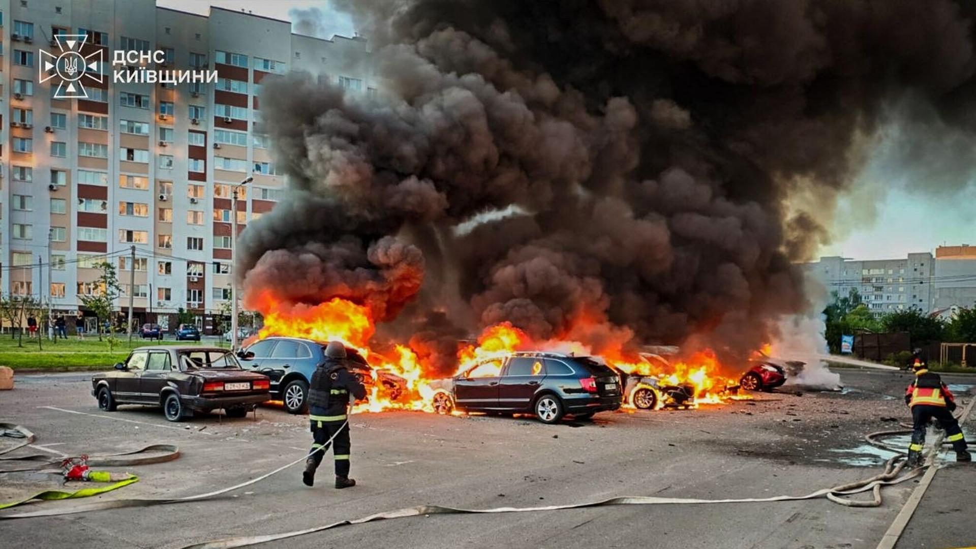 Ukrainische Feuerwehrmänner versuchen mehrere Autos, die in Flammen stehen, zu löschen.
