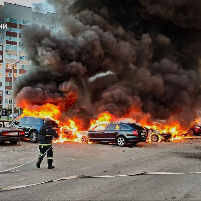 Ukrainische Feuerwehrmänner versuchen mehrere Autos, die in Flammen stehen, zu löschen.