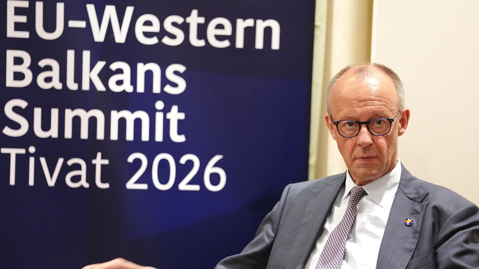 Tivat: Bundeskanzler Friedrich Merz (CDU) sitzt vor einem Wand mit der Aufschrift "EU-Western Balkans Summit Tivat 2026".