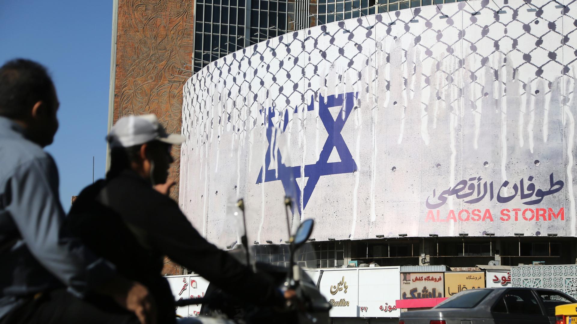 Auf der weißen Fassade eines halbrunden Gebäudes hängt ein Plakat mit dem Davidstern und der Aufschrift "Aqsa Flut" (Übersetzung).
