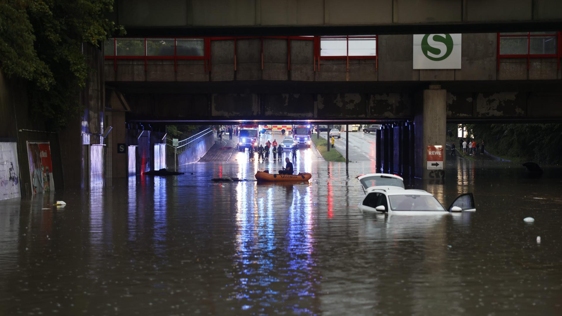 Einsatzkräfte der Feuerwehr können nur noch mit einem Schlauchboot zu den Autos in einer überschwemmten Unterführung gelangen.