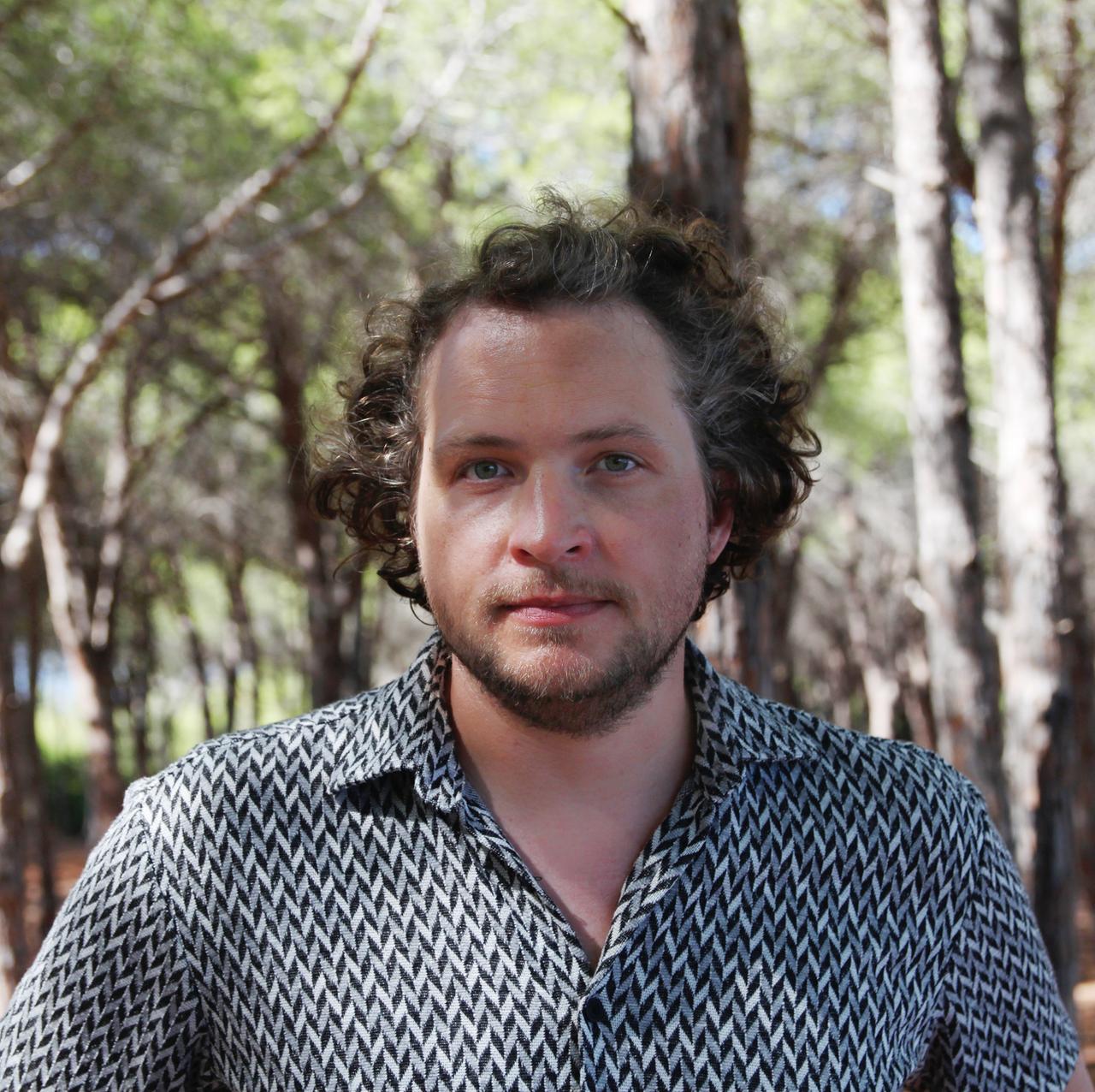 Stephan Dorn in kariertem Hemd von einem verschwommenen Wald im Hintergrund. Stephan Dorn in kariertem Hemd von einem verschwommenen Wald im Hintergrund.