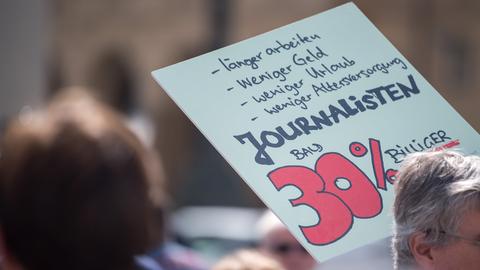Mit einem Plakat mit der Aufschrift "Journalisten bald 30% billiger" nimmt ein Journalist an einer Demonstration in der Münchener Innenstadt teil. 