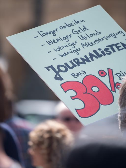 Mit einem Plakat mit der Aufschrift "Journalisten bald 30% billiger" nimmt ein Journalist an einer Demonstration in der Münchener Innenstadt teil. 