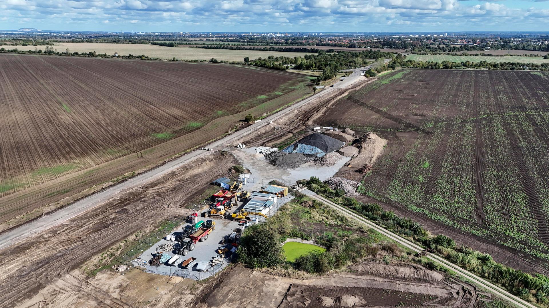 Vogelperspektive auf ein Feld mit einer Zufahrtsstraße, auf der Baufahrzeuge geparkt sind. Vogelperspektive auf ein Feld mit einer Zufahrtsstraße, auf der Baufahrzeuge geparkt sind.