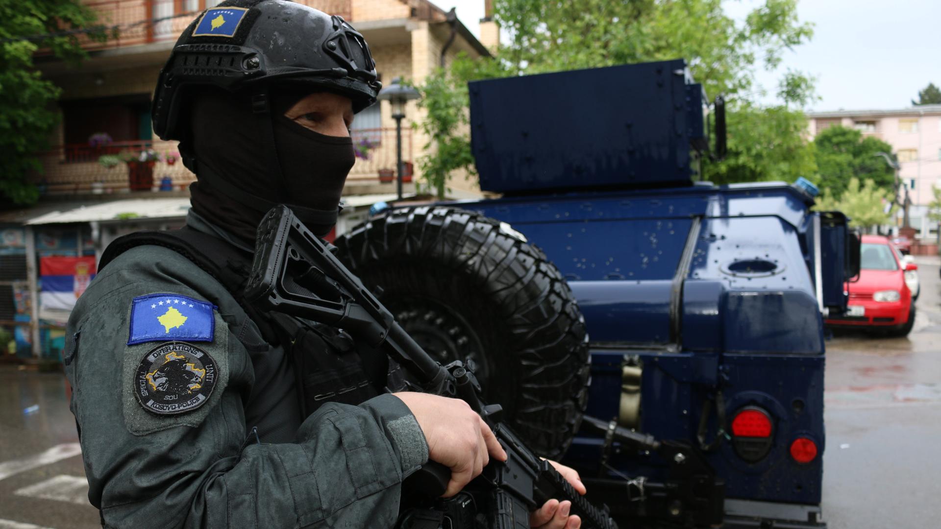 Ein kosovarischer vermummter Polizist mit Helm und Maschinenpistole.