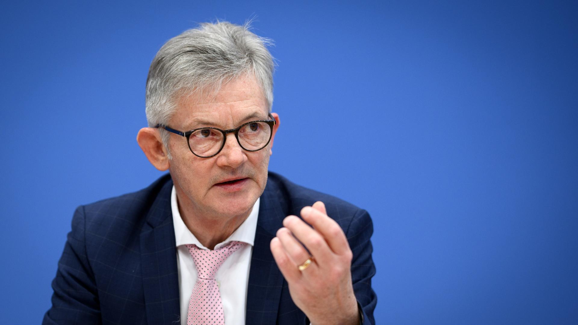 Der grauhaarige Spiegler redet und gestikuliert vor der blauen Wand der Bundespressekonferenz. Der grauhaarige Spiegler redet und gestikuliert vor der blauen Wand der Bundespressekonferenz.
