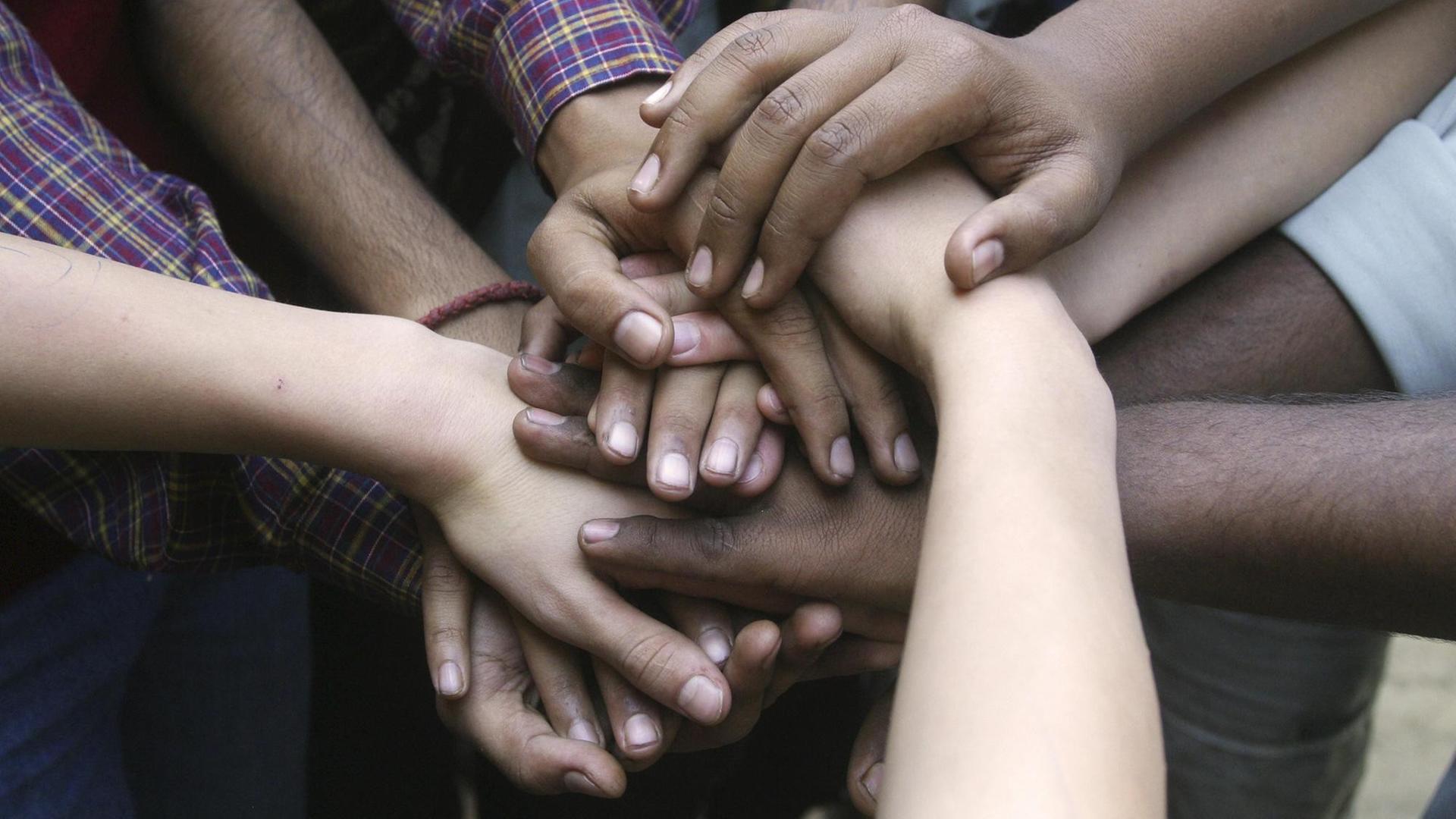Indische und deutsche Hände, freundschaftlich aufeinandergelegt