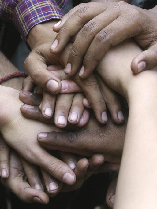 Indische und deutsche Hände, freundschaftlich aufeinandergelegt