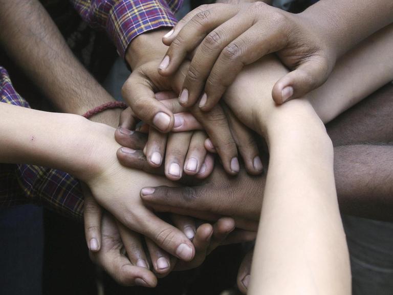 Indische und deutsche Hände, freundschaftlich aufeinandergelegt