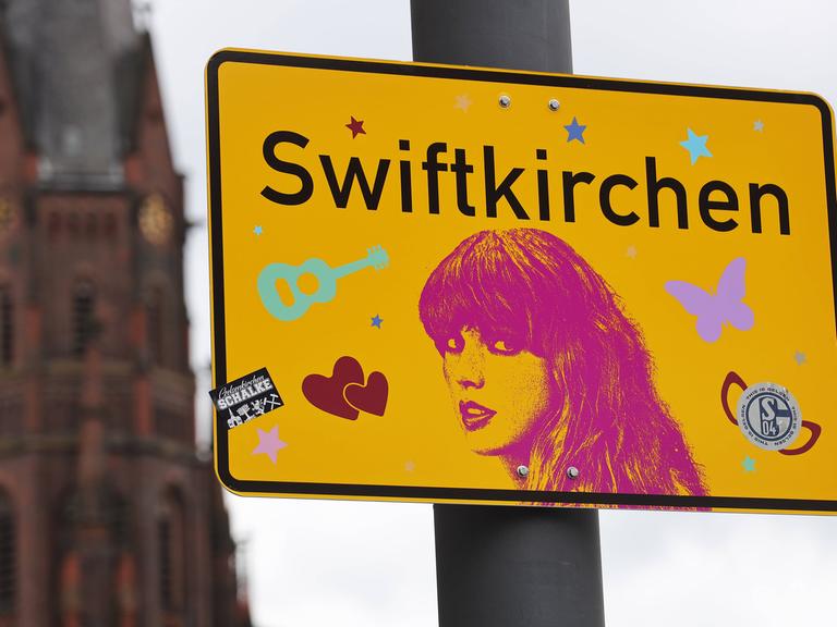 Ein Schild mit der Aufschrift Swiftkirchen statt Gelsenkirchen und einem Konterfei der Sängerin Taylor Swift, die im Juli drei Konzerte in der Arena auf Schalke gibt.
