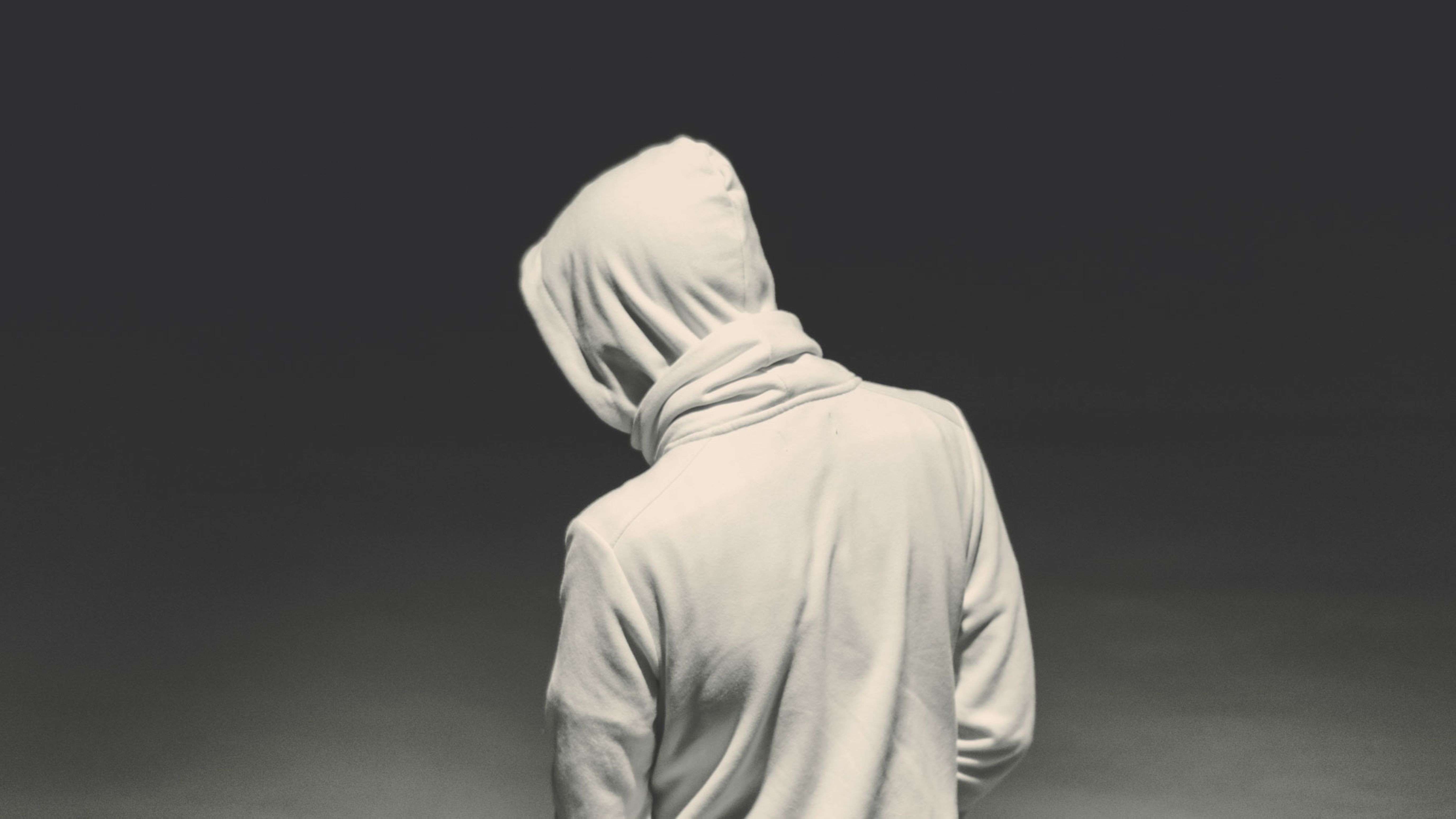 Ein junger Mann von hinten mit einem weißen Hoodie mit über den Kopf gezogener Kapuze