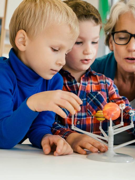 Kitakinder beim Betrachten eines Modells unseres Sonnensystems