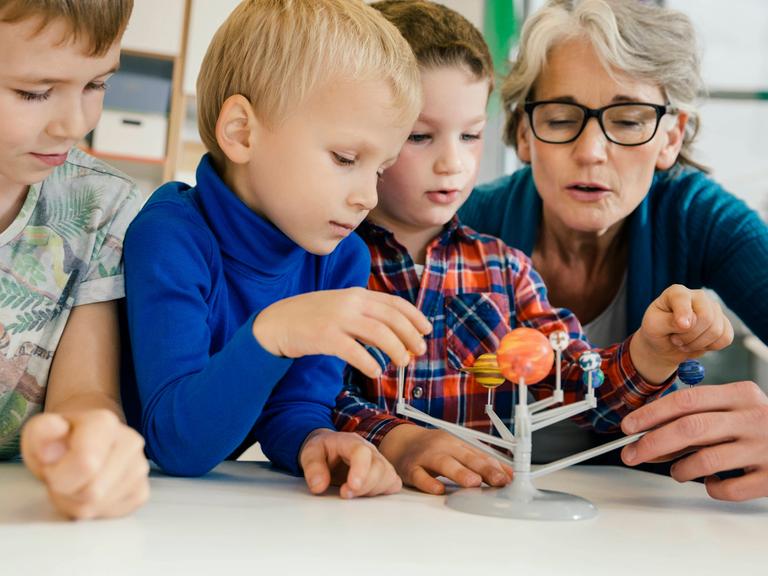 Kitakinder beim Betrachten eines Modells unseres Sonnensystems