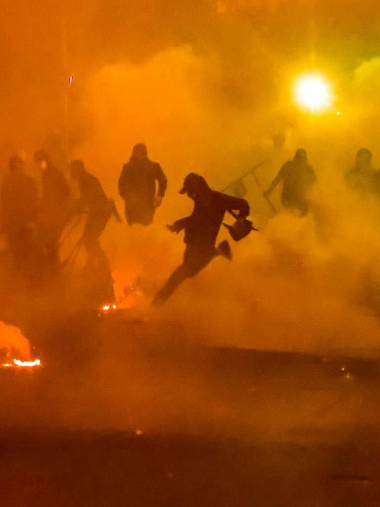 Im Gegenlicht einer rötlichen Tränengaswolke sind die Schatten von Demonstranten zu sehen. 