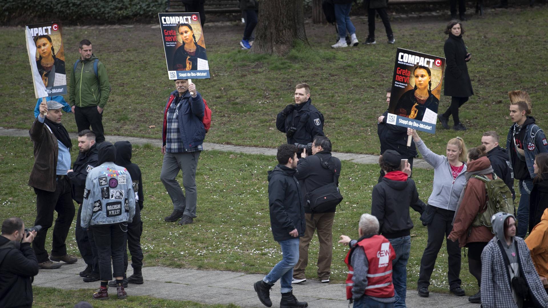 Verstreute Einzelpersonen halten am Rand einer Demonstration Bilder hoch, auf denen die Klimaaktivistin Greta Thunberg und der Schriftzug "Greta nervt" zu sehen ist.